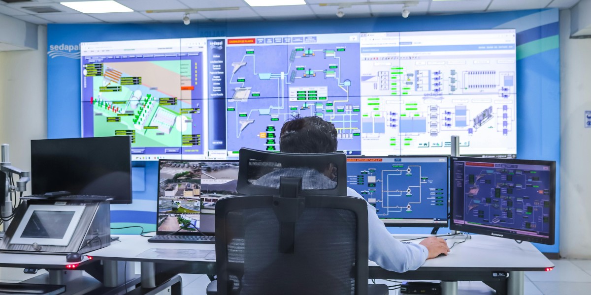 Person sitting at desk with multiple monitors in a cyber security room with monitors all along the front of the room