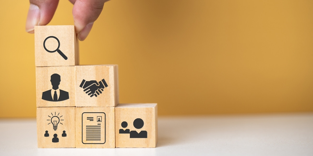 Six wooden blocks with icons representing various human resources activities being stacked on a tabletop