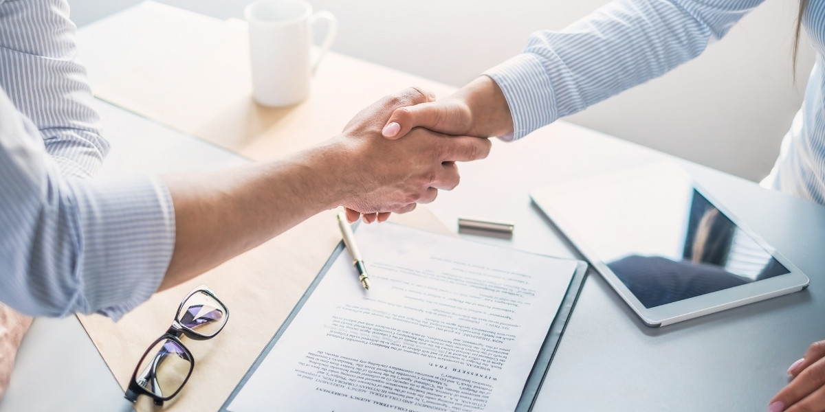 Two people shaking hands over an open manila folder displaying a document they have signed