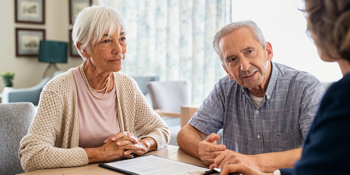 A senior couple at a meeting with a business person reviewing forms on the table