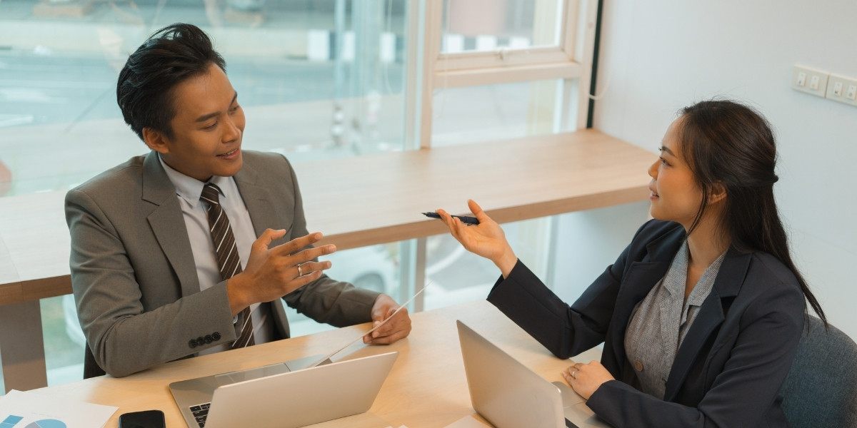 Two people sitting at a table in a negotiation conversation.