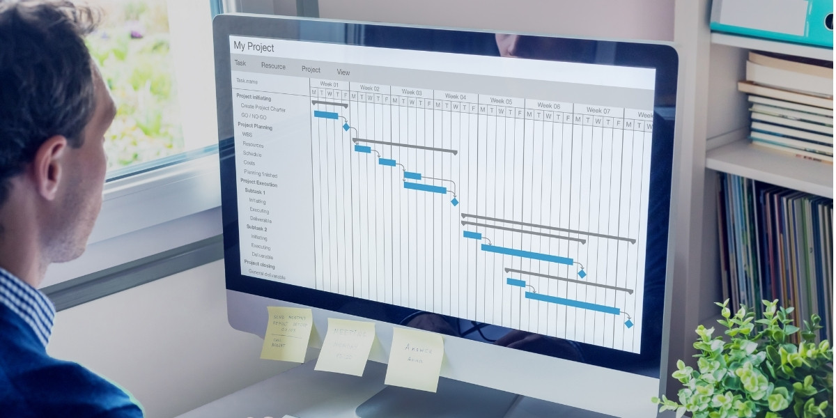A project manager reviewing their project timeline on a large computer monitor