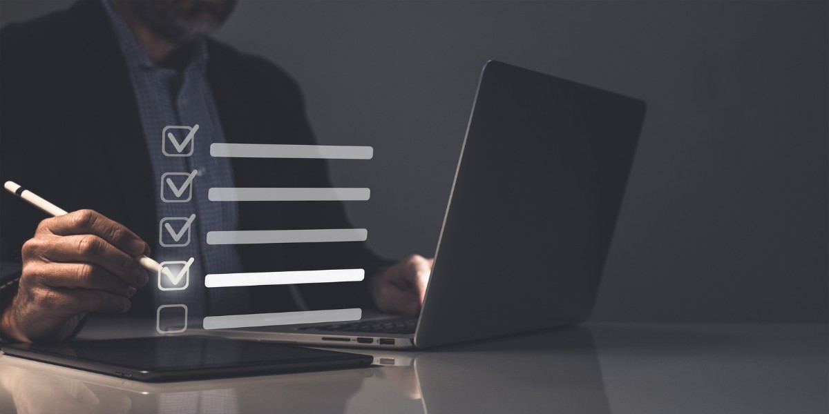 A person at a desk working on a laptop with a graphic of a checklist floating on the page